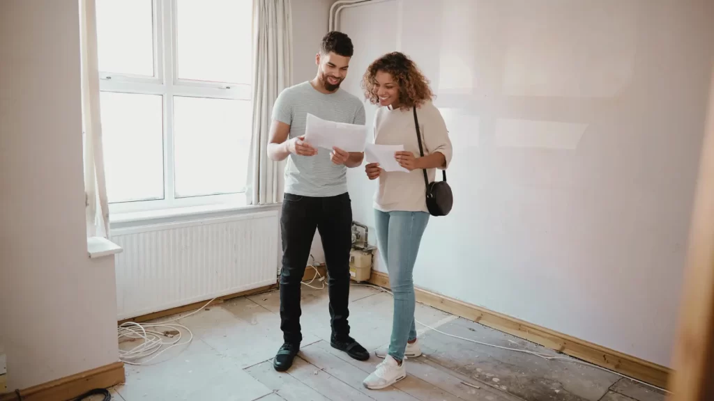 couple-examining-house-plans-in-empty-room